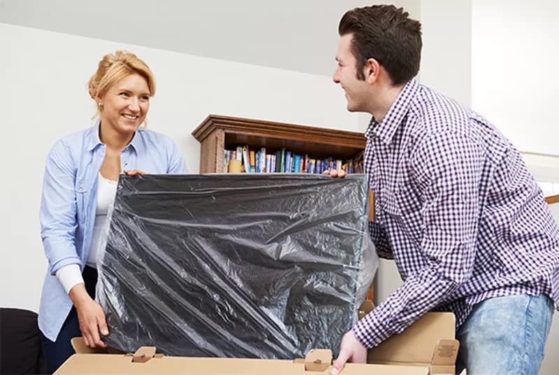 a man and woman removing a new tv from a box